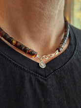 Load image into Gallery viewer, Person wearing a beaded necklace with a silver charm on a black shirt.