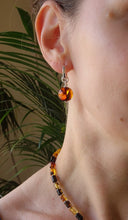 Load image into Gallery viewer, Close-up of a person wearing an amber-colored earring with a blurred background