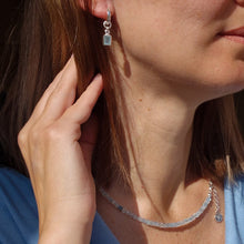 Load image into Gallery viewer, A beaded necklace with light blue aquamarine stones and a handmade silver medallion with a spiral design.